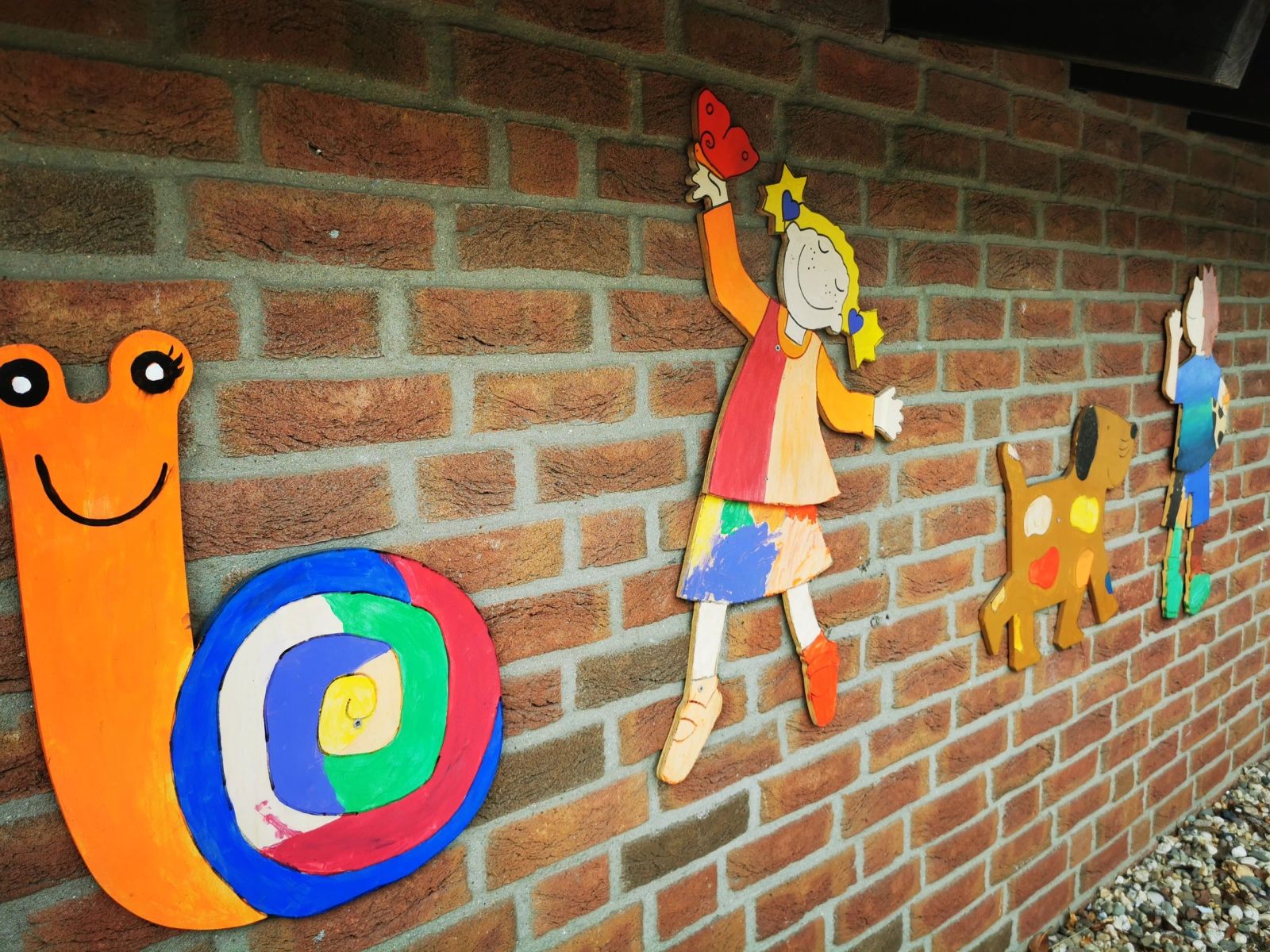 Bunte Holzfiguren am Kindergartenhaus